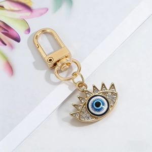 Macro shot of evil eye keychain with blue enamel, sparkling rhinestones and golden clasp