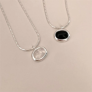 Detail of silver necklaces featuring black onyx and white shell oval pendants