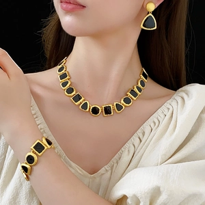 Close-up of vintage geometric gold necklace and earring set with black resin inlay