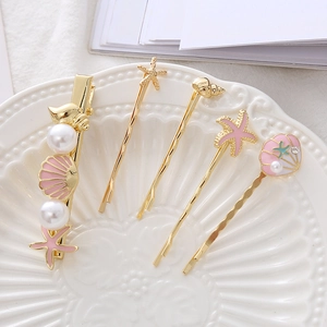 Close-up of ocean-themed starfish and seashell hair clips set in a ceramic dish