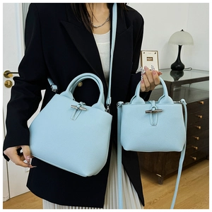 Detail of light blue lychee pattern leather bucket bag with metallic bamboo toggle closure