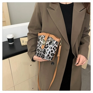Close-up of leopard print bucket bag with brown leather trim and metal twist lock detail