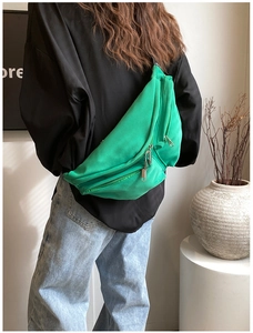Detail view of vibrant green crossbody bag with multiple zip compartments on model