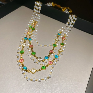 Multilayer gold necklace with white pearls and colorful crystals on a premium display