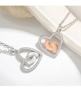 Close-up of heart-shaped pendants with baby footprints in silver and rose gold