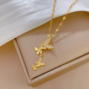 Titanium steel gold necklace with sparkling zircon butterfly pendants on silk background