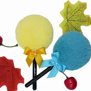 Detail of plush lollipop powder puff with long fibers, ribbon bow, and black handle wand