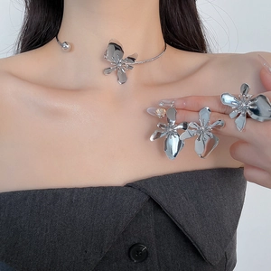 Detailed view of model wearing silver metallic floral necklace and matching ring jewelry set