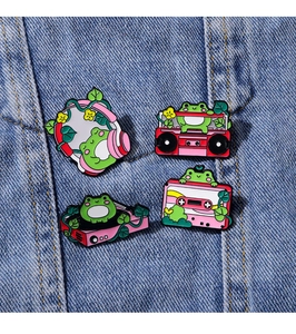 Detailed macro view of green cartoon frog enamel pins on blue denim fabric background
