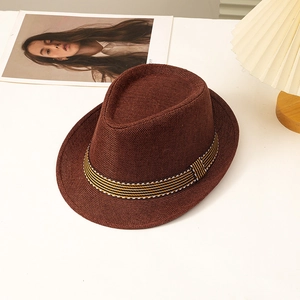 Deep brown straw fedora with striped band on a white table for summer sun protection