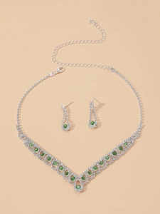 Détail du collier en V et boucles d'oreilles avec pierres vertes et strass argentés