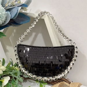 Macro detail of black sequined crescent bag with sparkling crystal-encrusted handle
