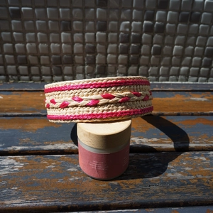 Detail of handwoven raffia headband with red textured patterns on a vintage jar