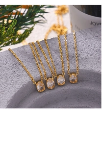 Minimalist gold oval zircon pendant necklaces draped on a grey stone bowl in a natural setting