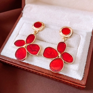 Detailed macro of red floral earrings with gold edges on a velvet jewelry box cushion