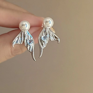 Detail of fishtail pearl earrings with small blue heart stone in silver finish