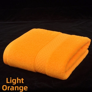 Detail of light orange cotton bath towel showing wavy jacquard hem and soft terry texture