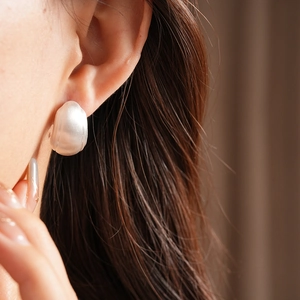Detailed close-up of matte silver irregular C-shape earring showing the textured metal finish