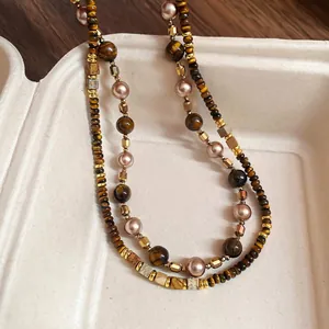 Vintage tiger eye stone pearl necklace with gold metal beads on a textured tray