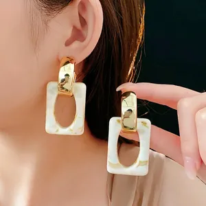 Chic geometric C-shape drop earrings featuring gold metal and white marble resin texture