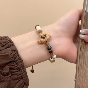 Detail of hand-woven bracelet with brown teddy dog ceramic bead and tiger eye stones