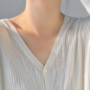 Détail du collier ras du cou doré à perles porté pour un look minimaliste et élégant