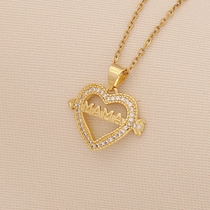 Detail shot of a gold heart pendant featuring MAMA engraving and a sparkling crystal