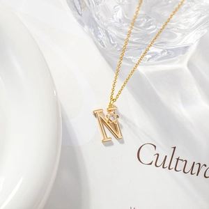 Detail view of a gold initial N necklace featuring a zircon floral accent on a fine chain