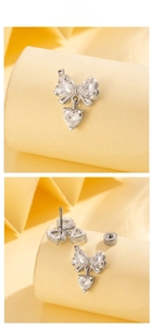 Macro detail of silver titanium steel bow heart earring with sparkling zircon inlays
