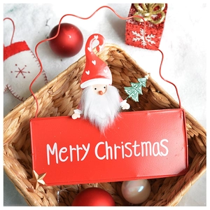 Macro view of a red metal Merry Christmas sign with a Santa figurine on a basket edge