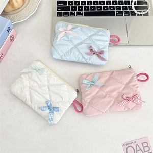 Three-piece set of quilted macaron cosmetic bags with bow details and metal zippers