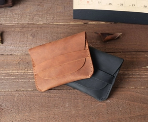 Retro handmade leather card holders in brown and black on a rustic wooden desk