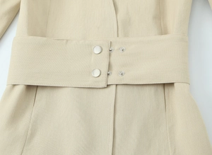 Détail de la taille d'un blazer beige avec large ceinture et boutons-pression en métal
