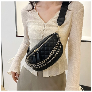 Detail of quilted black waist bag with double gold chains and wide fabric strap