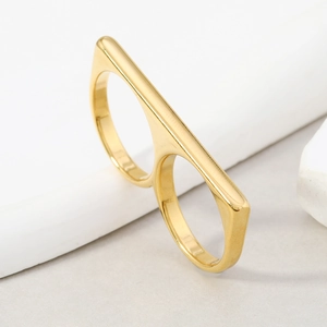 Macro detail of golden hollow double finger ring on white stone surface in minimalist style