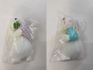 Close-up of plush Easter bunnies holding a purple carrot and a blue polka dot egg