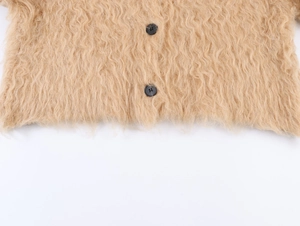 Dettaglio macro del cardigan beige peloso con trama in ecopelliccia e bottoni neri tondi