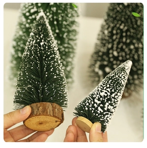 Detail of mini snowy Christmas trees featuring real wood base and frosted green pine needles