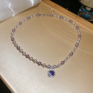 Macro detail of purple and white pearl necklace with sparkling square zircon pendant