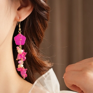 Détail de boucles d'oreilles fleur rose et perles à pampilles avec crochets dorés