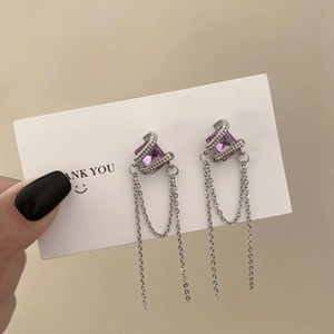 Detail of long tassel earrings featuring a purple square gemstone and silver chain fringes