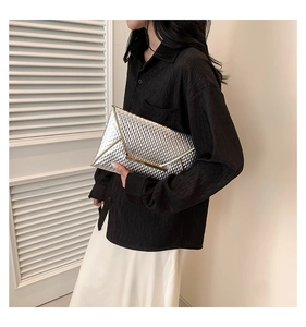 Detail of silver envelope clutch bag featuring metallic texture and gold bar clasp
