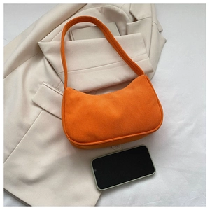 Flat lay of an orange corduroy baguette bag on a beige blazer with a smartphone detail