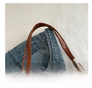 Détail de la poignée en cuir marron et du tissu denim bleu avec ruban à chevrons