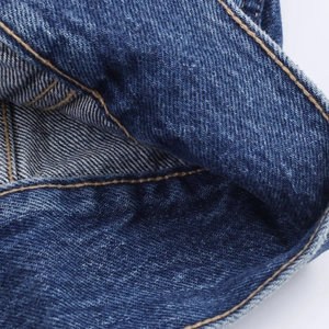 Macro detail of high-quality navy denim fabric with durable yellow contrast stitching
