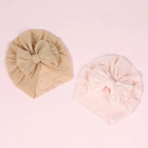 Detailed flat lay of beige and pink lace baby turbans with large decorative bows