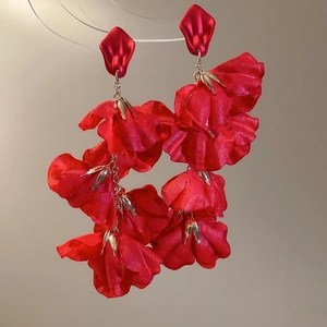 Close-up of red fabric flower drop earrings with layered silk petals and gold chain detail