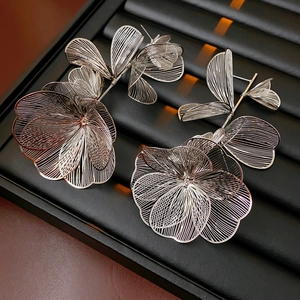 Close-up of silver hollow flower stud earrings with artistic metal cutout design