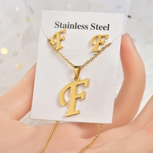 Dettaglio del set di gioielli in acciaio inossidabile dorato con collana e orecchini lettera F