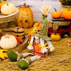 Detail of harvest gnome doll with green straw hat and orange plaid dress in fall setting